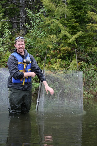 Jesse Weber standing knee-deep in a stream next to sampling equipment